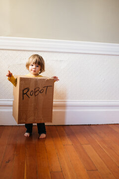 A child stands in a DIY style cardboard box robot costume.