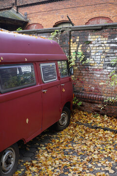 Old camper van in front of a wall in fall