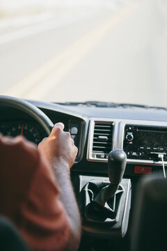 Inside view of a vehicle dashboard and a man hand on the steering wheel during a trip on a highway