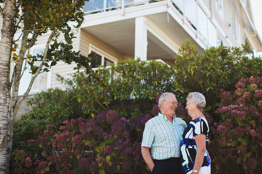Happy senior couple outside enjoying life together with ouse behind