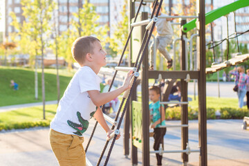 Obraz premium Happy child is playing at a playground. Young caucasian child is playing on the playground