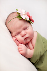 Newborn Baby Girl Sleeping Peacefully in Green Blanket, Wearing Flower Headband, Spring
