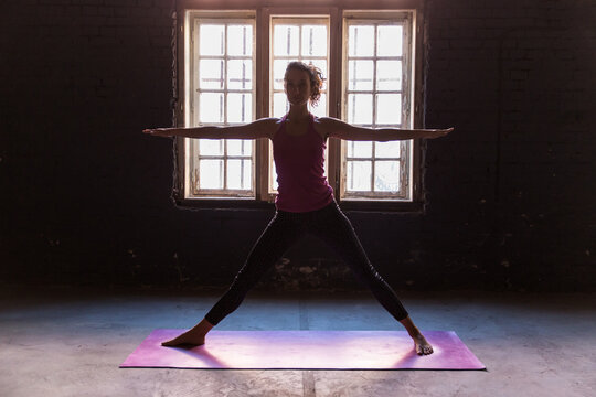Woman doing warrior yoga pose in a studio