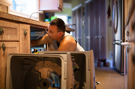 Man fixing a double drawer dishwasher in his home