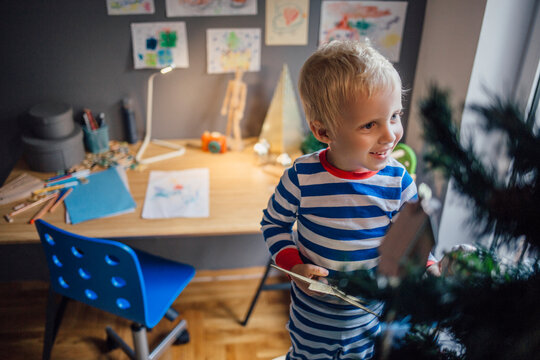 Blond Boy Standing on a Chair and Decorating the Christmas Tree