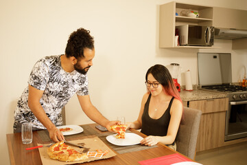Obraz na płótnie Canvas Pareja de novios comiendo pizza en casa viendo telefono inteligente