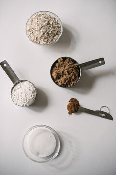 Flour, cinnamon, sugar, rolled oats ingredients in measuring cups for apple crisp