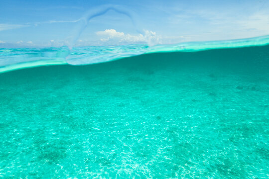 Emty half turquoise tropical sea water half blue sky background