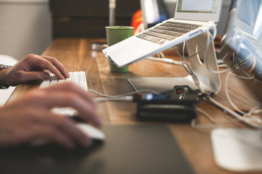 Man types on wireless keyboard and uses mouse while working in office.