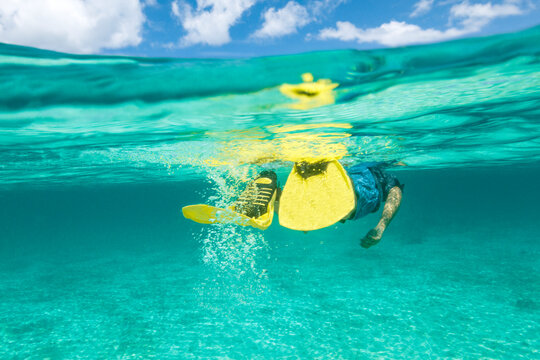 Half water half sky photo of a young man snorkeling in tropical turquoise water on one of Thailand islands