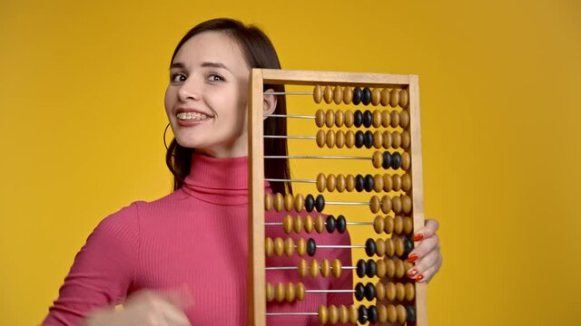 Young attractive girl holds wooden abacus in her hands.