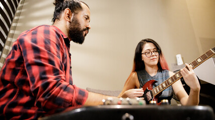 Fototapeta na wymiar Pareja joven latina mexicana tocando musica juntos en sala