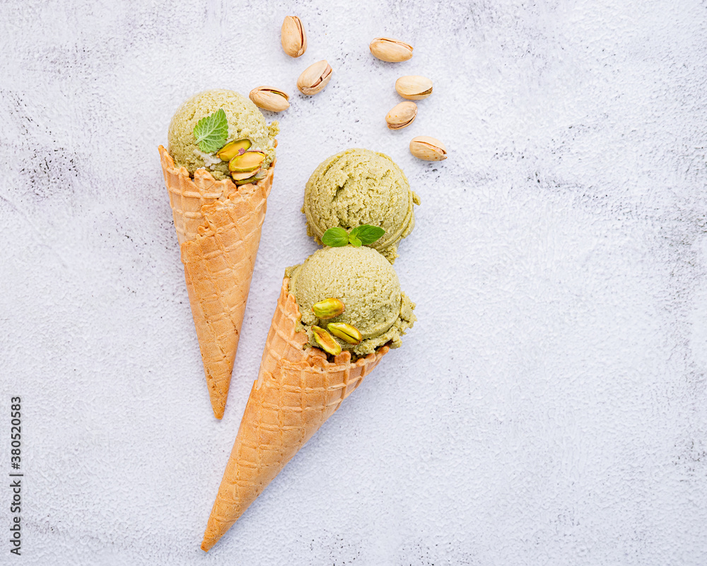 Poster pistachio ice cream in cones with pistachio nuts setup on white stone background . summer and sweet 