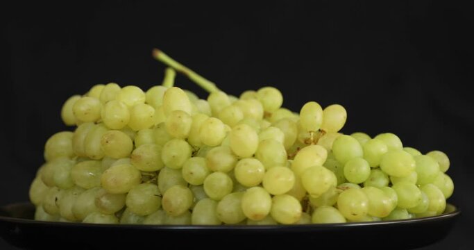 Bunch of white ripe grapes rotating on black background