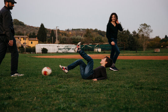 Boy fell tp the ground while playing soccer with his father