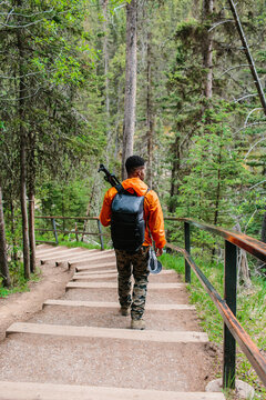 A man walking down a stair case trail with his camera gear & tripod