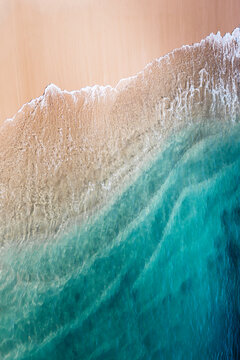 Beautiful turquoise clear sea waves reeaching the sandy shore seen from the air