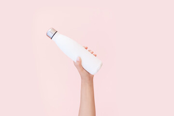 Close-up of female hand holding reusable, steel eco thermo water bottle of white, isolated on...