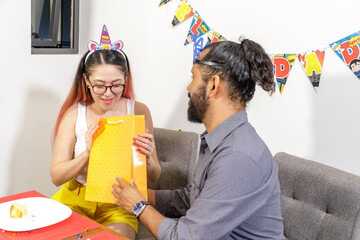 Pareja de jovenes mexicanos novios recien casados intercambian regalos durante cumpleaños en casa
