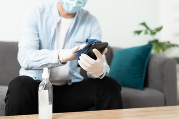 Careful man disinfecting cellphone