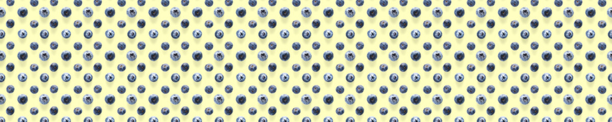 Background of Freshly picked blueberries on yellow backdrop.