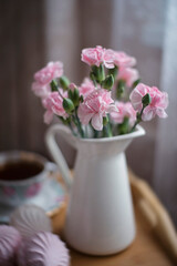 Still-life. A bouquet of pink carnations on a tray with pink marshmallows.