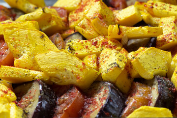 Fried potatoes with vegetables, sprinkled with seasoning close-up.