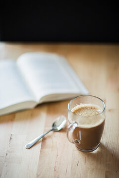 Coffee and latte mug in front of open book on table