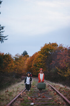 Kids dressed up like fox and raccoon walking on train tracks