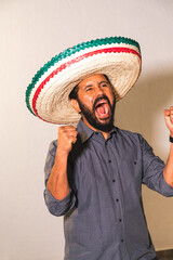 Retrato de hombre joven mexicano hispano latino con sombrero gritando con felicidad emoción dia de...