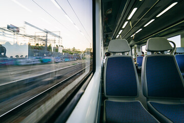 Half view of the train tracks from the window and the inside empty seats of the train