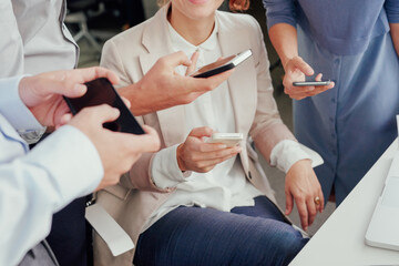 Close crop of diverse business peoples hands using smart phones