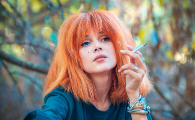 Girl with red hair smokes a cigarette