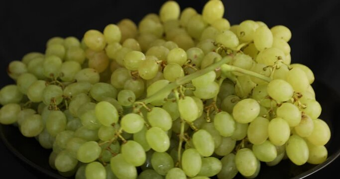 Bunch of white ripe grapes rotating on black background