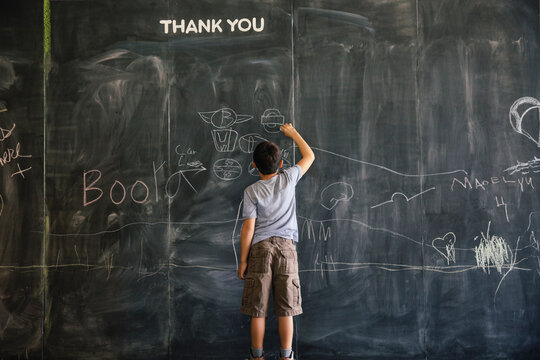 Boy drawing on a large chalkboard paint wall