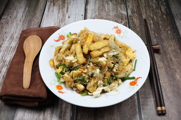 Fried and stirred fresh vermicelli with dried tofu, shrimp, egg, chilly and spring onion on the plate. Hot and spicy street food menu in Asia restaurant. 