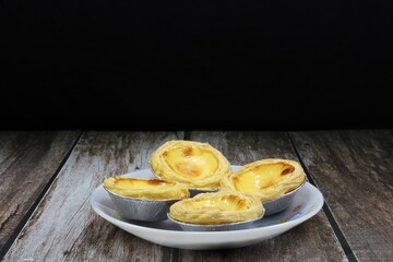 Pile of baked classic egg tart serving on the plate. Famous traditional sweet dessert in party or ceremony. 