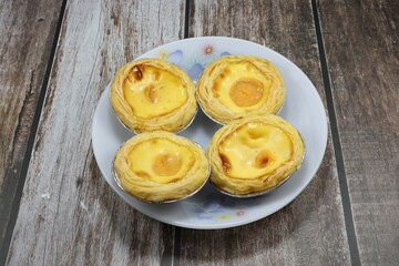 Pile of baked classic egg tart serving on the plate. Famous traditional sweet dessert in party or ceremony. 