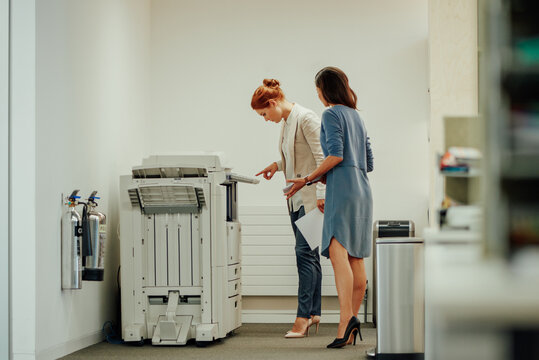 Young businesswomen figuring out how to use photostat machine