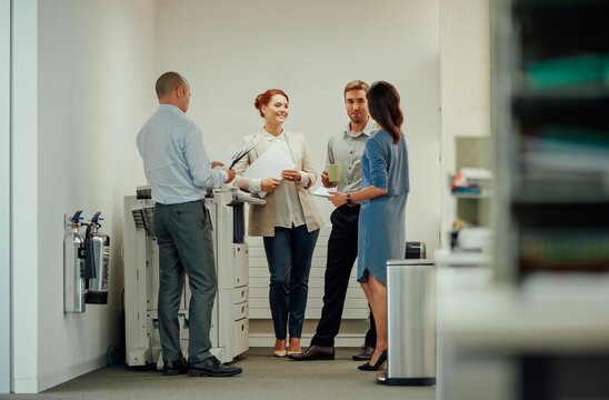 Young diverse business people interacting next to office photocopier