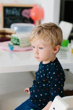 Thoughtful young boy in front of birthday cakes