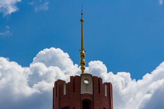 A golden spire over a building against a blue sky
