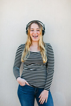 Woman laughing with braces and listening music with headphone.