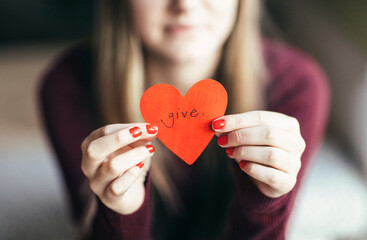 Female holding a red paper heart with the word Give written on it