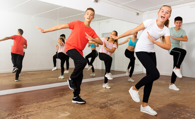 Fototapeta na wymiar Teenage dancers practicing active vigorous dance in modern studio..