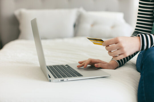 Closeup of a woman shopping online with her credit card from home.