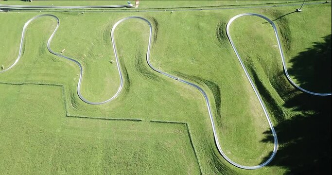 Amazing drone aerial view of a summer bobsleigh track. Passo della Presolana. Bergamo, Italy. Natural contest. Leisure time. Beautiful nature with green meadow. Vertical landscape