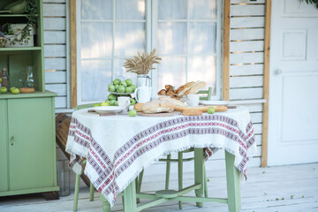 Country style kitchen table. Table in the yard of the house. There are rolls, bread and spikelets on the table
