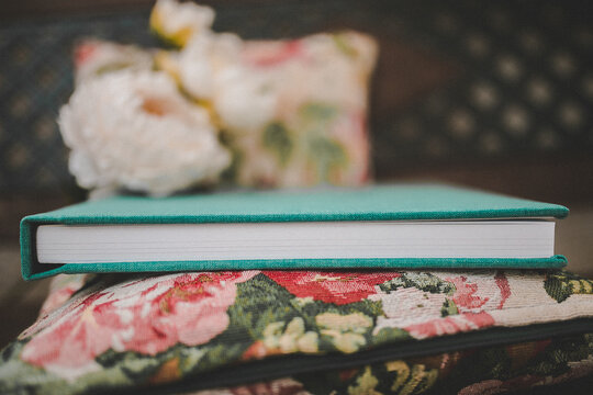 Pretty vintage green photo book detail laying on a floral cushion