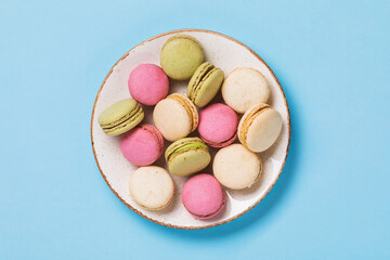 Full plate of various macaroons on blue background, top view